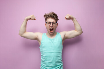 non-athletic guy with glasses shows biceps on a yellow background and shouts, motivated nerd shows...
