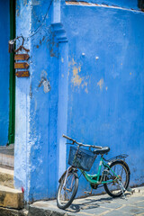 Fototapeta na wymiar A bicycle with a basket leaning against a bright blue wall at Hoi An in Vietnam