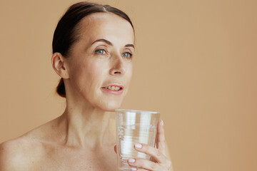 modern woman with glass of water isolated on beige