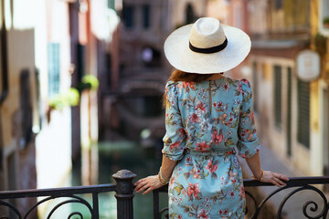 Seen from behind stylish traveller woman in floral dress