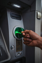Close up shot of a man inserting a credit card in an ATM outdoors to check the bank account.