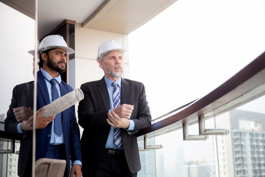 Senior Architect Inspector Talking With Contractor Man Together At Office While Holding Blueprint Building Structure, Executive And Engineer Planning Project, Industry And Construction Concept.