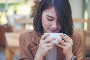 Close up Woman hand holding black coffee cup in green garden cafe. Hands of businesswoman love...