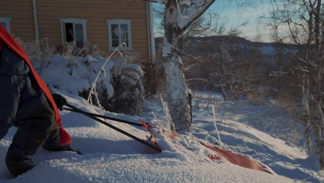 A boy pulling his led up the hill in knee-high snow during Christmas in Norway