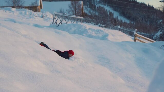Shot of a little kid having fun on the snow, enjoying the pleasures of sledding using red plastic shovel sled in Beitostolen, village in Oystre Slidre Municipality in Innlandet county, Beito, Norway.