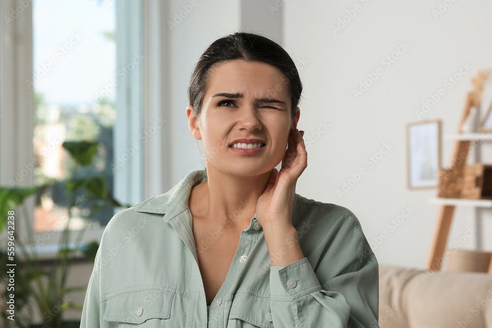 Sticker Young woman suffering from ear pain at home