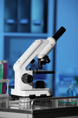 Modern microscope with glass slide on metal table in laboratory, toned in blue