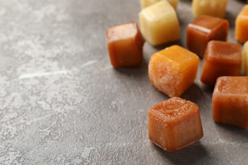 Different frozen fruit puree cubes on brown marble table, closeup. Space for text