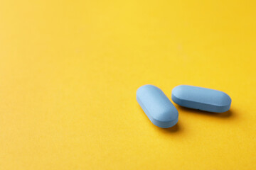 Pills on orange background, space for text. Potency problem