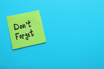 Paper note with phrase Don' t Forget on blue background, top view. Space for text