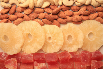 Different tasty nuts and dried fruits on beige background, flat lay