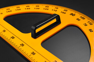 Yellow school protractor on blackboard, closeup view