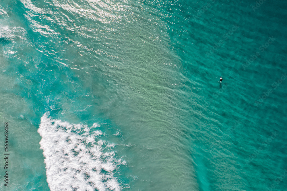 Wall mural surfers are seen from above in blue pristine ocean water - Wall murals
