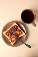 Tasty toast with chocolate paste and cup of tea served on light table, flat lay