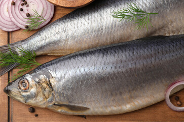 Board with delicious salted herrings, dill, onion and salt on wooden table, top view