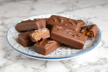 Delicious chocolate candy bars on white marble table, closeup