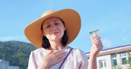 Woman straw hat against backdrop beautiful landscape sighs heavily, puts her hand heart, sympathetically shakes her head in her hands banknote money donation help. Tourist excursion experience charity