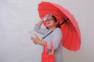 Asian woman, standing alone under red umbrella waiting for taxi
