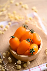 Fototapeta na wymiar Orange cherry tomatoes in wooden bowl, fresh organic vegetable