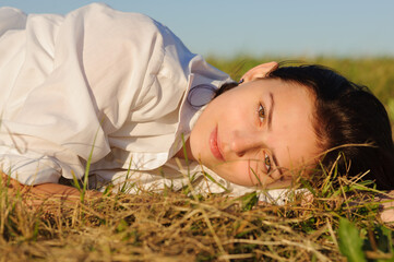 Young beautiful brunette woman lying on the green grass
