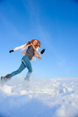 Naklejka na ściany i meble Pretty young woman with red hair take a fun on the snow field