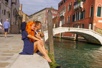 Fototapeta na wymiar Young couple sitting in the border of canal in Venice.