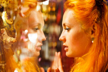 Close up portrait of woman with red hairs near shop window with masks