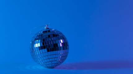 Fototapeta na wymiar Disco ball on a blurred blue background, the concept of dancing, disco, music and parties, copy space.
