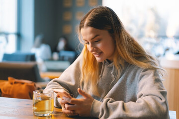 A young girl in a cafe uses the phone. People use technology. Cafe city lifestyle. Colorful...