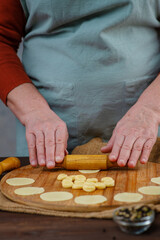 Hands of an elderly woman work with pieces of dest, making blanks for dumplings