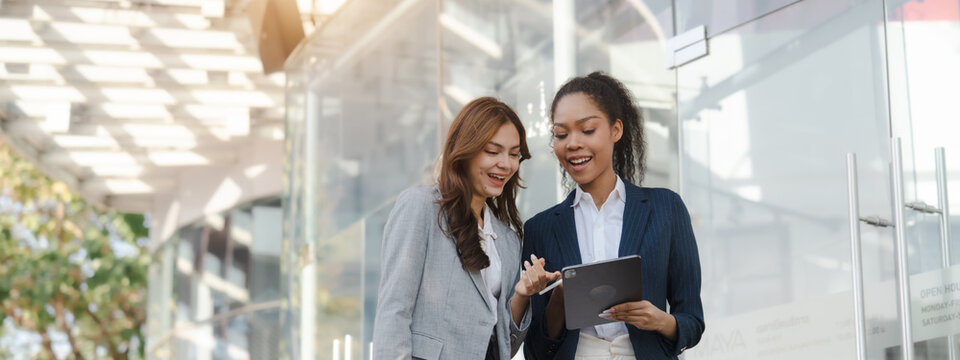 Two asia business women in conversation walking together on city street. Corporate colleagues workmate discussing new project while going to work. business outdoor.