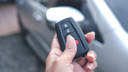 Hand holding car remote control, The back is a blurry car. Buying or selling a car concept.