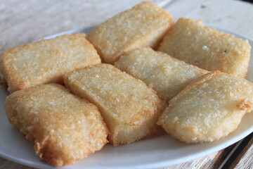 slices of traditional Indonesian food called fried sticky rice in a white plate on a wooden table