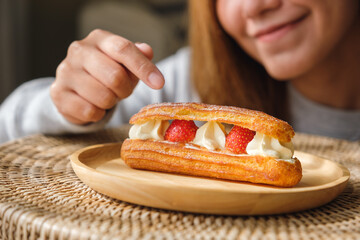 Closeup image of a woman pointing finger at a plate of strawberry Eclair