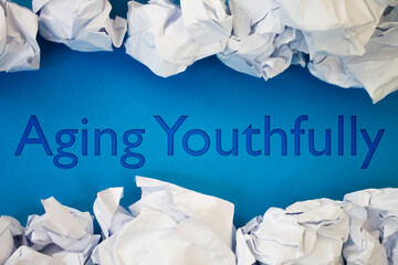 Aging Youthfully text with Torn, Crumpled White Paper on colored background.