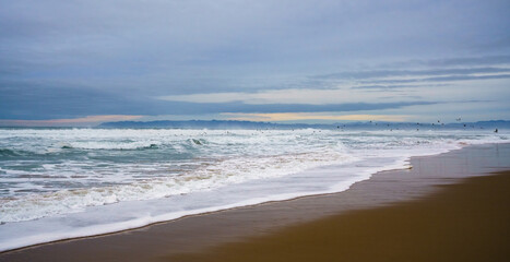 Dramatic seascape. Stormy Pacific ocean on a cloudy overcast day, and beautiful cloudy sky with silhouette of flying birds