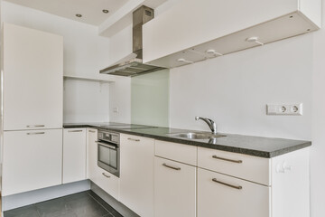 a kitchen with white cupboards and black counter tops on the counters in this photo is taken from...