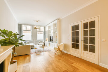 Naklejka premium a living room with hardwood flooring and white trim on the walls there is a large plant in the corner