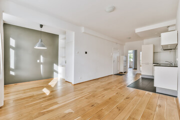 an empty living room with wood flooring and white appliances on the wall in the room is very light...