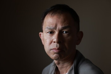 Fototapeta premium Middle-aged Japanese man in gray casual shirt on gray background. Conceptual image of world peace, stability in daily life, and sustainable living.