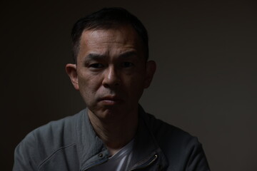 Fototapeta premium Middle-aged Japanese man in gray casual shirt on gray background. Conceptual image of world peace, stability in daily life, and sustainable living.