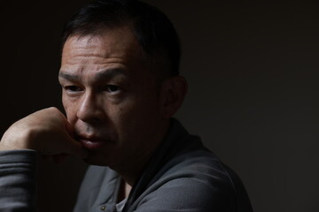 Middle-aged Japanese man in gray casual shirt on gray background. Conceptual image of world peace, stability in daily life, and sustainable living.