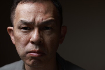 Fototapeta premium Middle-aged Japanese man in gray casual shirt on gray background. Conceptual image of world peace, stability in daily life, and sustainable living.