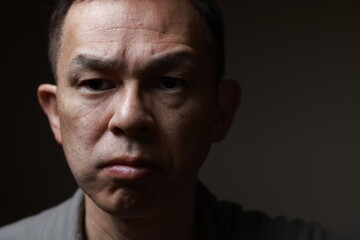 Fototapeta premium Middle-aged Japanese man in gray casual shirt on gray background. Conceptual image of world peace, stability in daily life, and sustainable living.