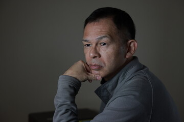 Fototapeta premium Middle-aged Japanese man in gray casual shirt on gray background. Conceptual image of world peace, stability in daily life, and sustainable living.