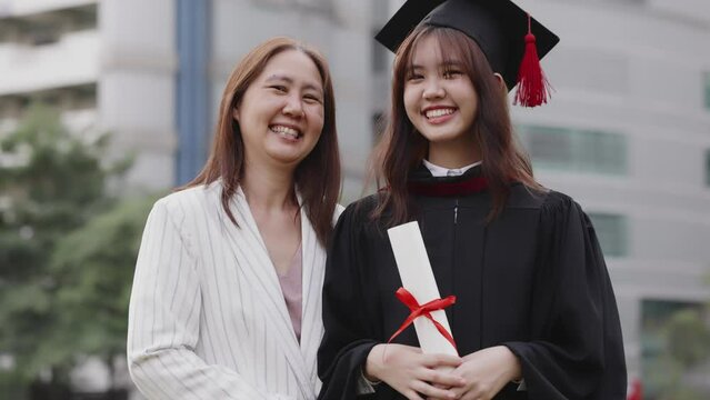 Happy Asian mother and graduated daughter take a picture in campus university together.