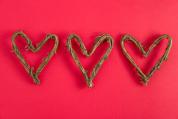 Heart shape made of dried grape vines on a red background, happy Valentine’s Day
