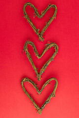 Heart shape made of dried grape vines on a red background, happy Valentine’s Day
