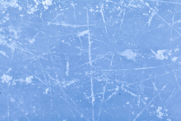 Empty ice rink with skate marks after the session outdoor. skating ice rink texture covered with snow in daylight. Close up of blue ice rink floor, copy space