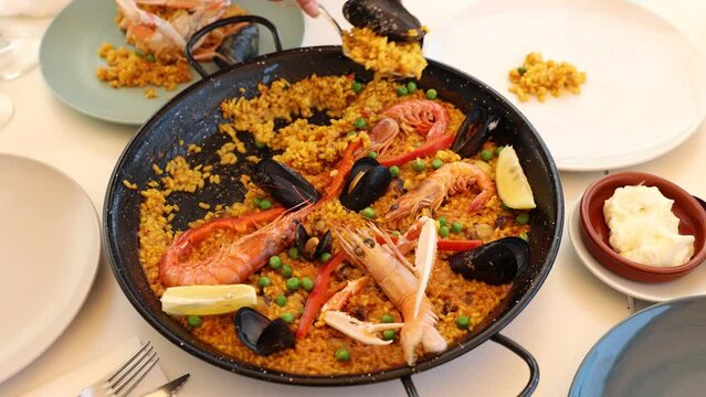 Portion of fresh seafood paella served on plate with piece of lemon.